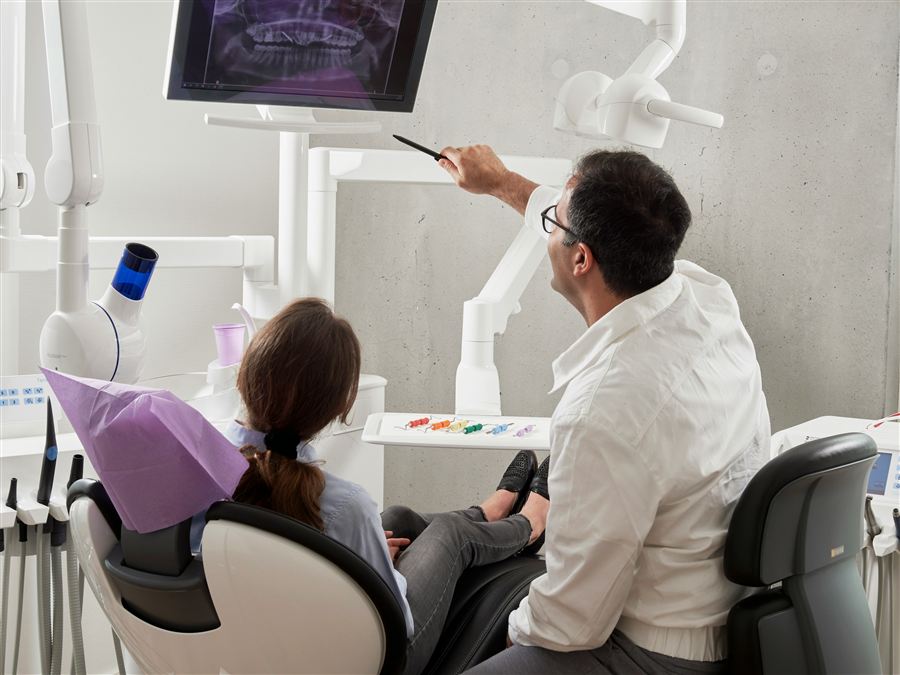 Dentist reviewing a patient's dental X-ray on a monitor during a consultation